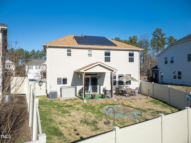 back of house with a yard, solar panels, and a fenced backyard