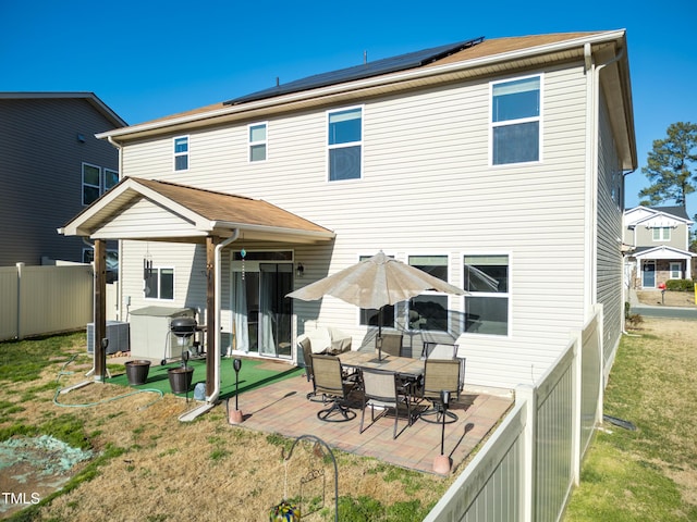 rear view of property with cooling unit, solar panels, a yard, a fenced backyard, and a patio area