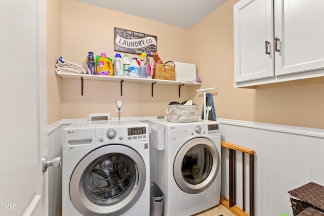 laundry room with cabinet space, washing machine and dryer, and wainscoting