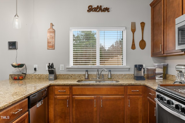 kitchen with light stone counters, brown cabinets, appliances with stainless steel finishes, and a sink