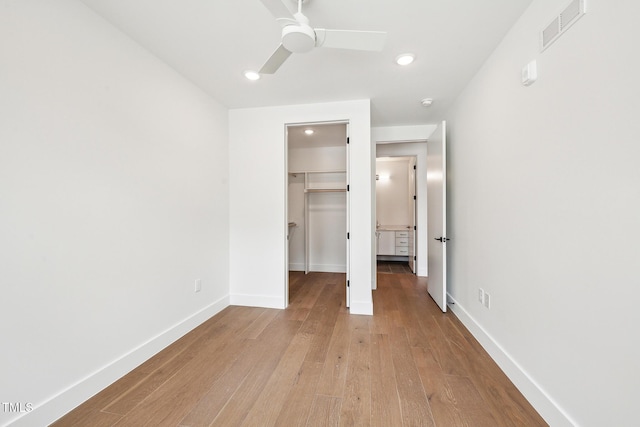 unfurnished bedroom featuring visible vents, baseboards, a spacious closet, light wood-style floors, and a closet