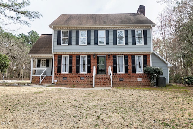 colonial house with crawl space, central AC unit, a chimney, and a front lawn