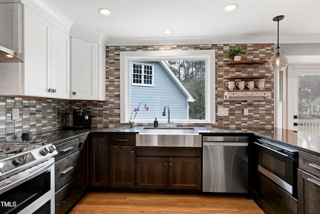 kitchen with tasteful backsplash, dark brown cabinetry, appliances with stainless steel finishes, and wall chimney exhaust hood