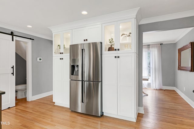 kitchen with white cabinetry, a barn door, stainless steel fridge with ice dispenser, and light wood-type flooring