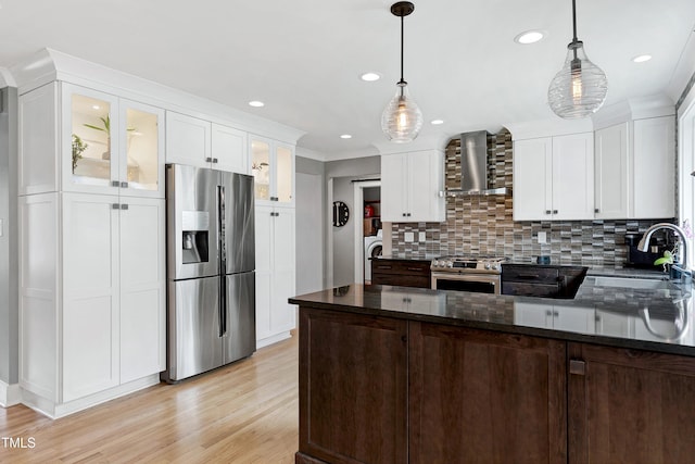 kitchen featuring white cabinetry, stainless steel appliances, wall chimney range hood, and a sink