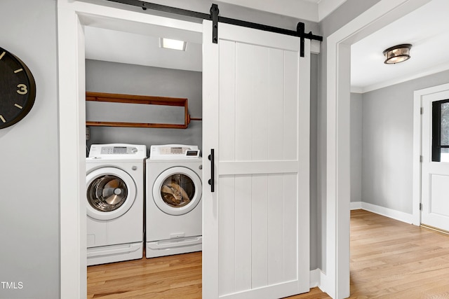 laundry area with laundry area, a barn door, wood finished floors, and washing machine and clothes dryer