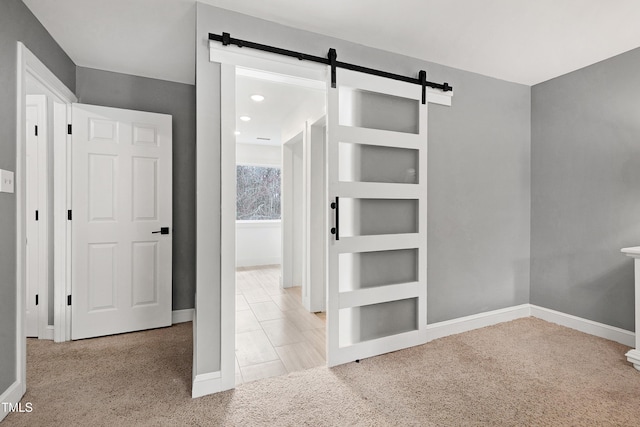 interior space featuring a barn door, baseboards, and carpet floors