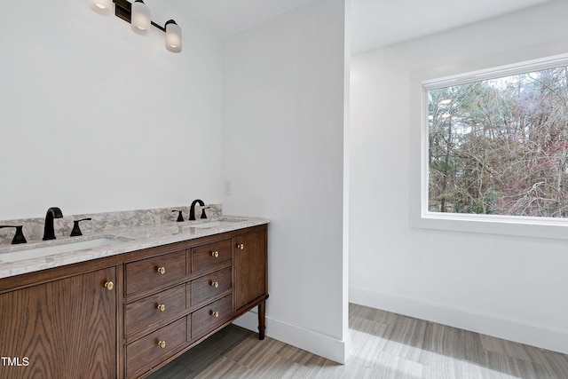 full bathroom featuring double vanity, baseboards, and a sink