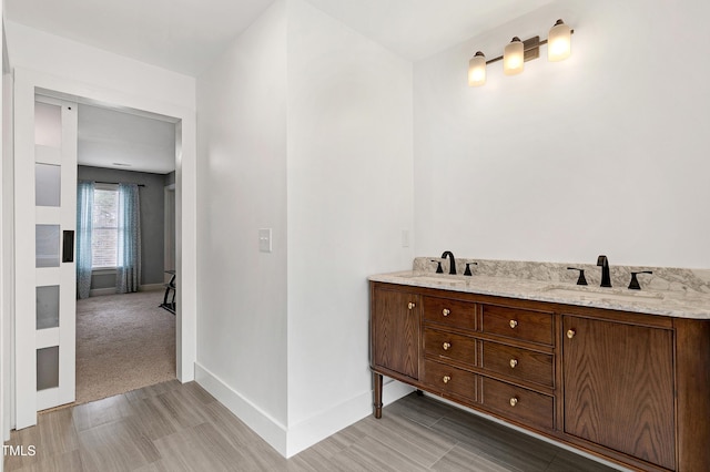 bathroom featuring a sink, baseboards, and double vanity