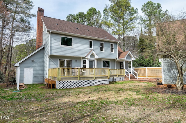 back of property with fence, a lawn, and a chimney