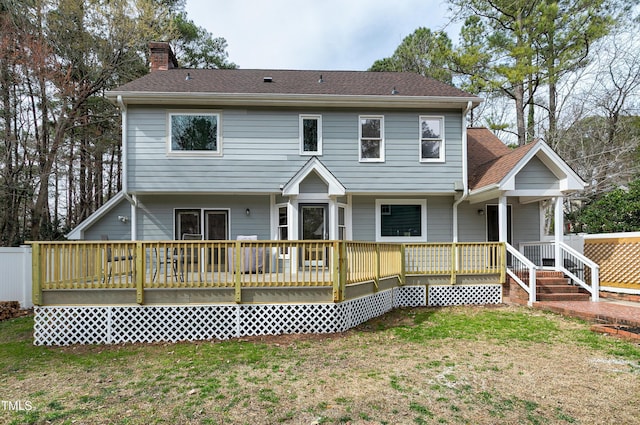 rear view of property featuring a lawn, roof with shingles, and a chimney