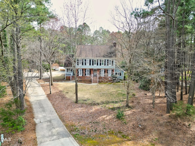 view of front of property featuring concrete driveway, brick siding, and a wooded view