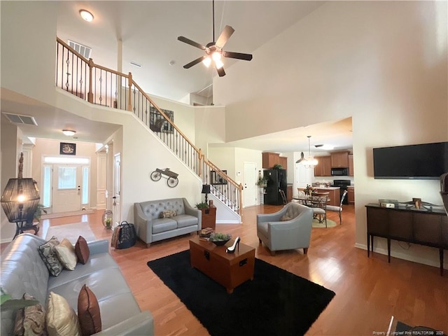 living area with stairway, light wood-style floors, visible vents, and ceiling fan