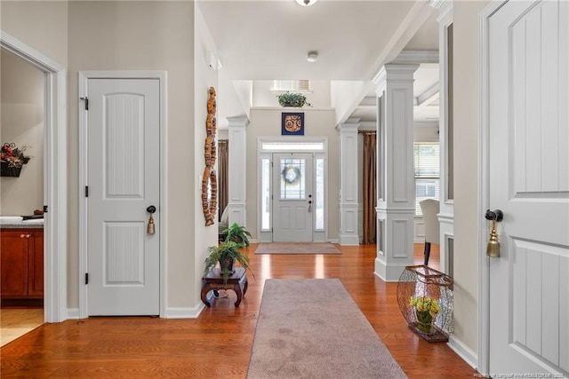 foyer with decorative columns, visible vents, wood finished floors, and a decorative wall