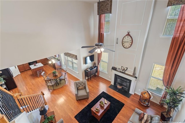 living room with baseboards, wood finished floors, a towering ceiling, and a ceiling fan
