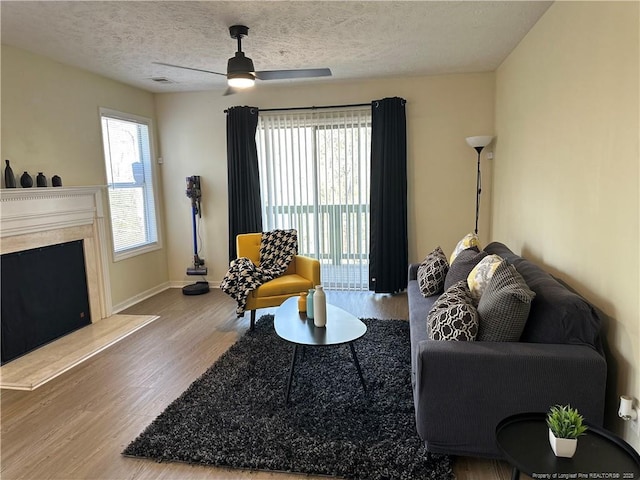 living room featuring visible vents, ceiling fan, baseboards, wood finished floors, and a textured ceiling