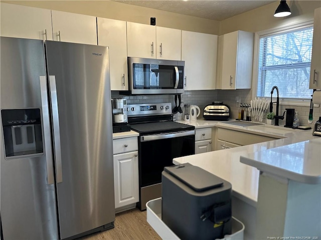 kitchen with backsplash, appliances with stainless steel finishes, white cabinets, and light countertops