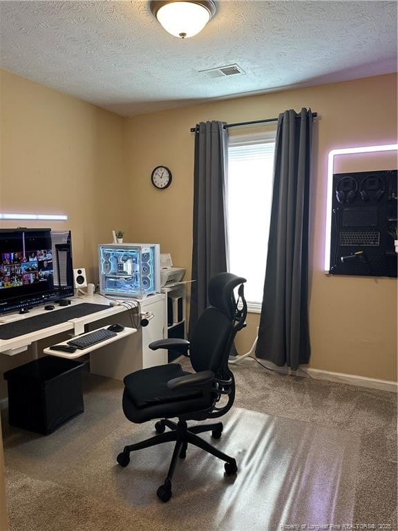 carpeted office with visible vents, baseboards, and a textured ceiling