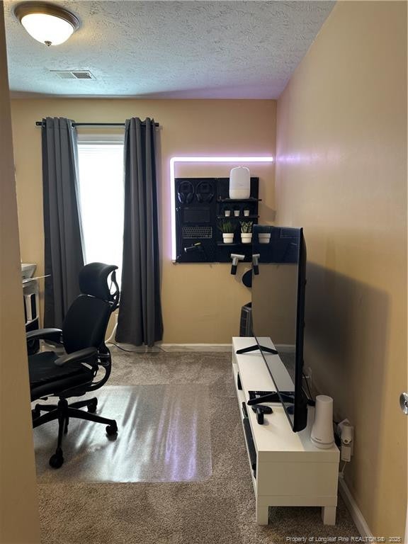 home office with baseboards, visible vents, carpet floors, and a textured ceiling