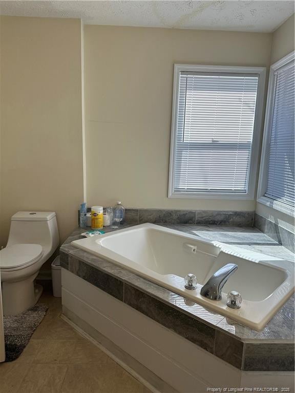 full bathroom with tile patterned floors, toilet, a bath, and a textured ceiling