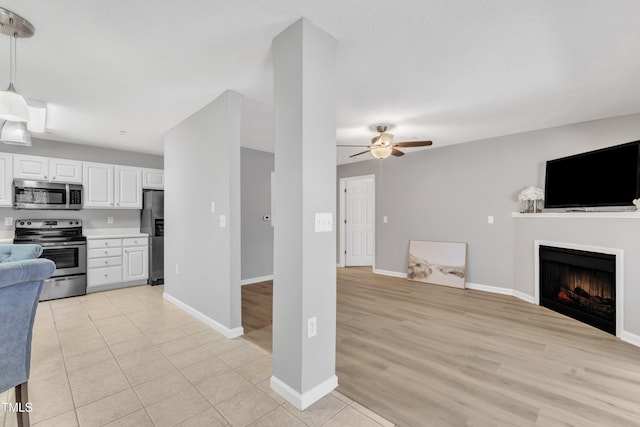 kitchen featuring ceiling fan, stainless steel appliances, light countertops, white cabinetry, and open floor plan