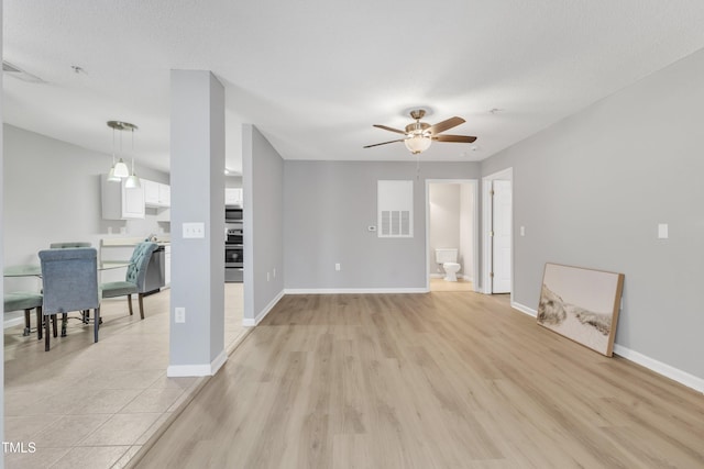 living room featuring visible vents, baseboards, light wood-style floors, and ceiling fan