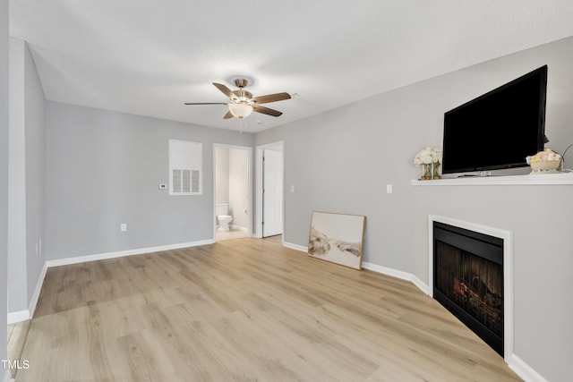 unfurnished living room with visible vents, a fireplace, light wood finished floors, baseboards, and ceiling fan