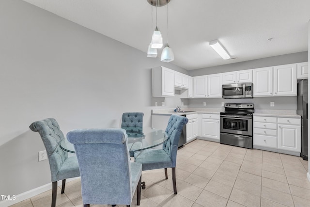 kitchen with decorative light fixtures, white cabinetry, stainless steel appliances, light countertops, and light tile patterned floors