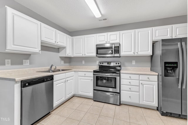 kitchen featuring a sink, white cabinetry, stainless steel appliances, light countertops, and light tile patterned floors