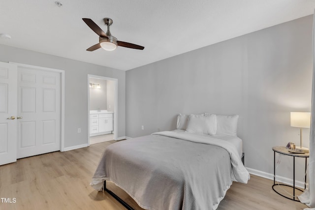 bedroom featuring baseboards, light wood-style floors, and ensuite bathroom