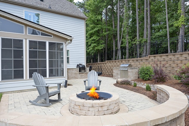 view of patio / terrace with area for grilling, an outdoor fire pit, a sunroom, and fence