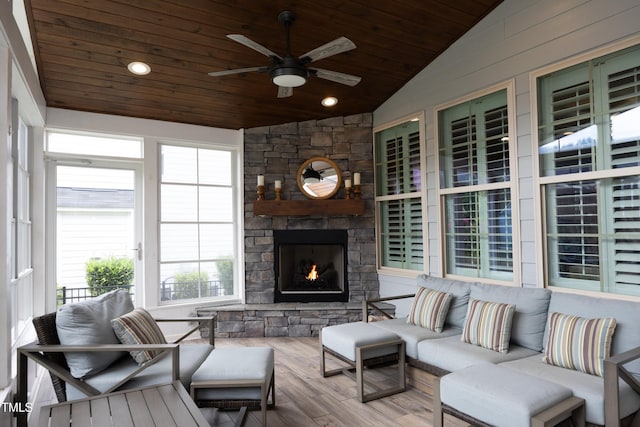 interior space featuring lofted ceiling, a stone fireplace, wooden ceiling, and a ceiling fan