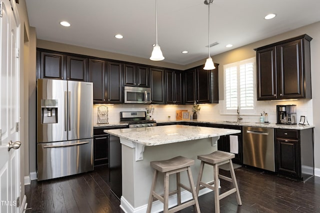 kitchen with dark wood finished floors, a kitchen island, tasteful backsplash, and stainless steel appliances