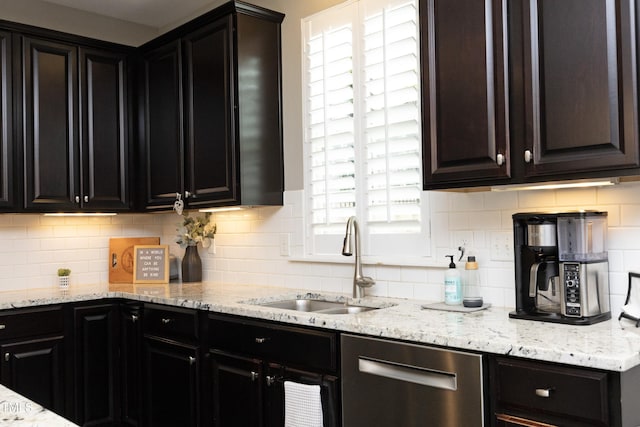 kitchen with a sink, backsplash, light stone countertops, and stainless steel dishwasher