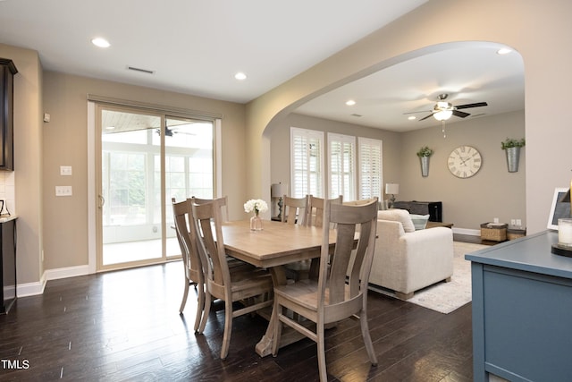 dining room featuring arched walkways, a healthy amount of sunlight, ceiling fan, and dark wood-style flooring