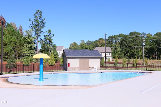 pool with a patio area, an outdoor structure, and fence