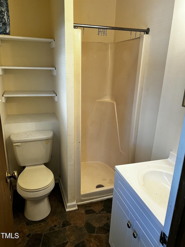 full bath featuring stone finish flooring, vanity, toilet, and a shower stall