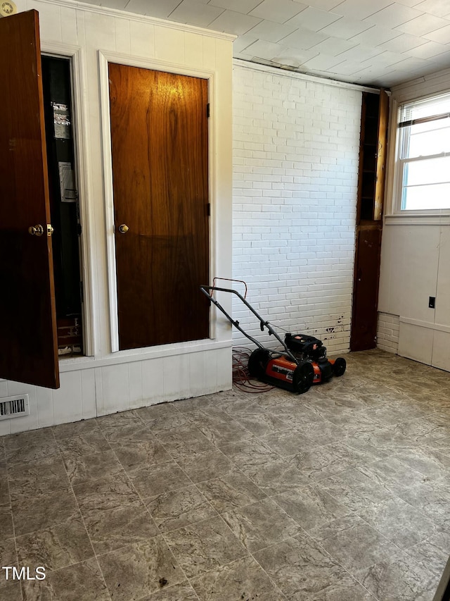 unfurnished room with visible vents and brick wall