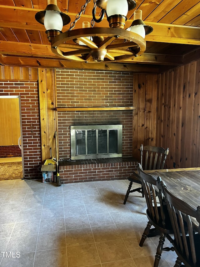 living area featuring beam ceiling, wooden walls, a brick fireplace, and wooden ceiling