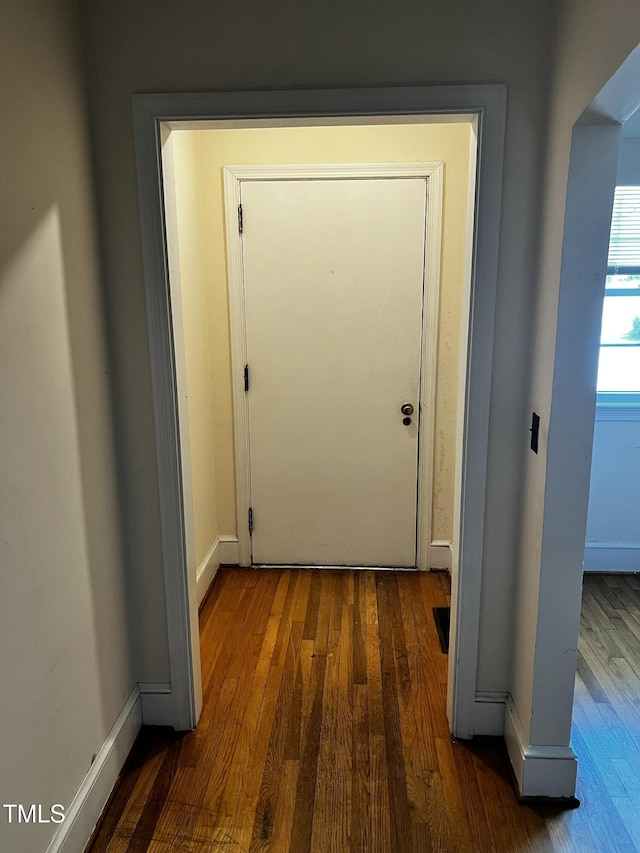 doorway to outside featuring baseboards and wood finished floors