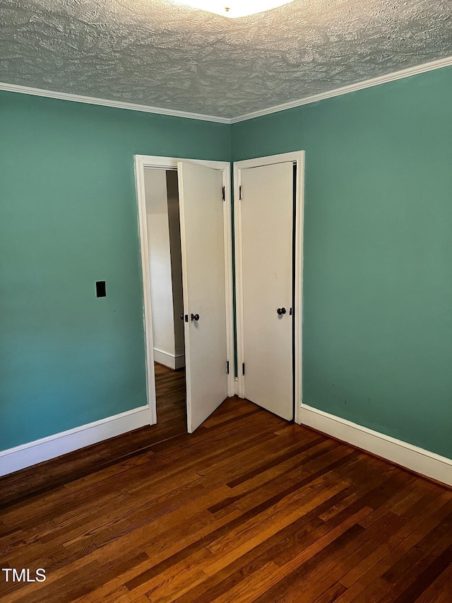 unfurnished bedroom featuring ornamental molding, a textured ceiling, hardwood / wood-style floors, a closet, and baseboards