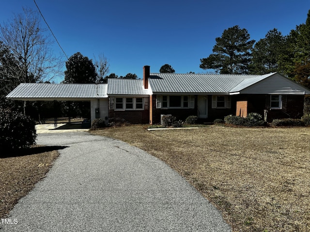 single story home with brick siding, aphalt driveway, metal roof, an attached carport, and a chimney