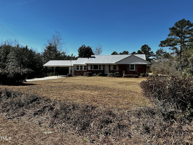 view of front of home with an attached carport, metal roof, and a front yard