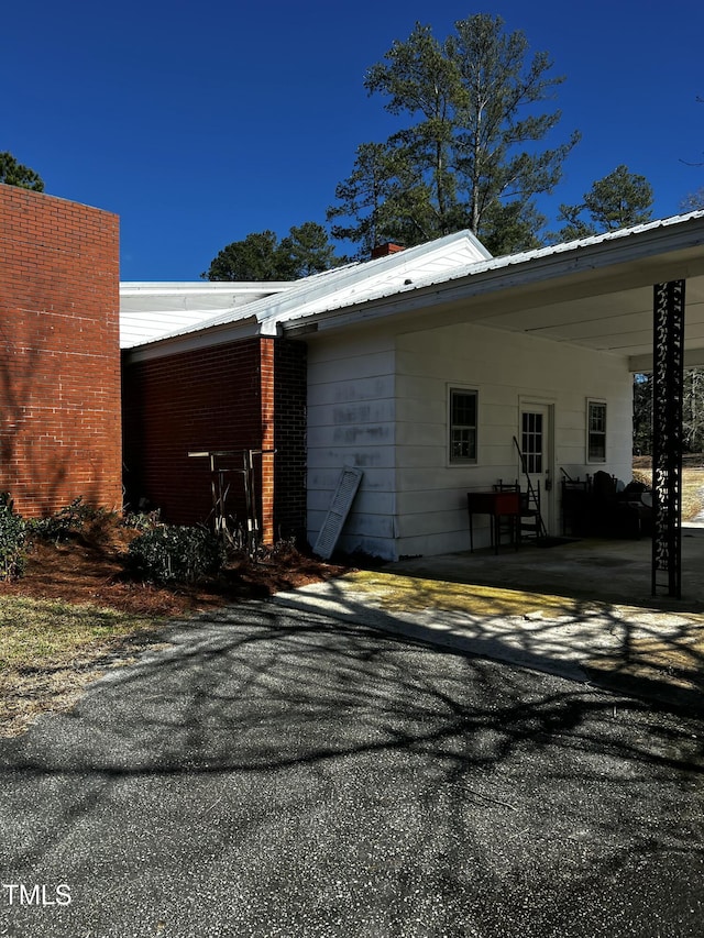 view of property exterior with an attached carport and metal roof