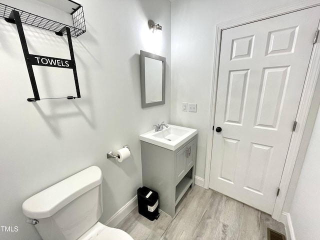 bathroom with vanity, baseboards, toilet, visible vents, and wood finished floors