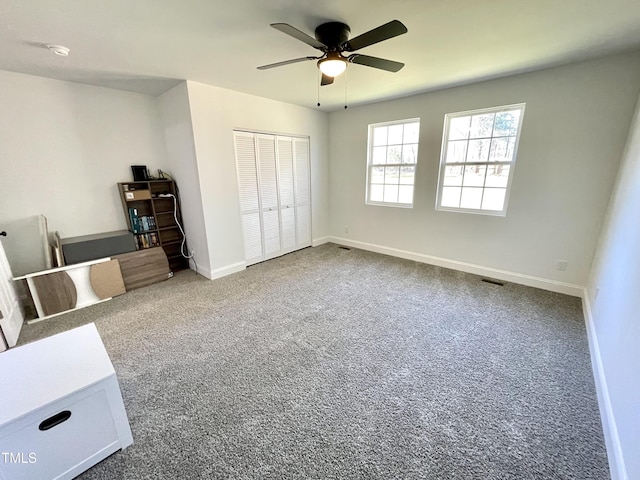 unfurnished bedroom with a closet, baseboards, carpet flooring, visible vents, and ceiling fan