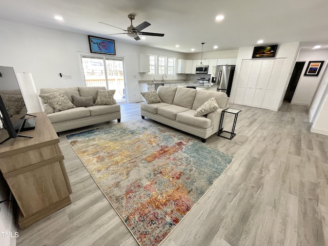 living area with light wood-style flooring, baseboards, a ceiling fan, and recessed lighting