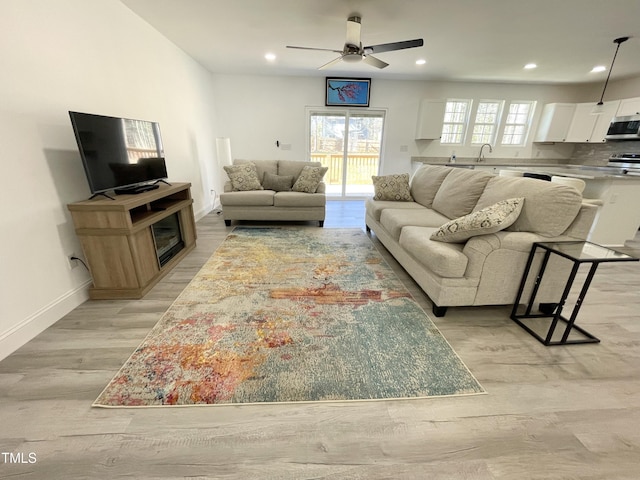 living room featuring ceiling fan, light wood-type flooring, recessed lighting, and baseboards