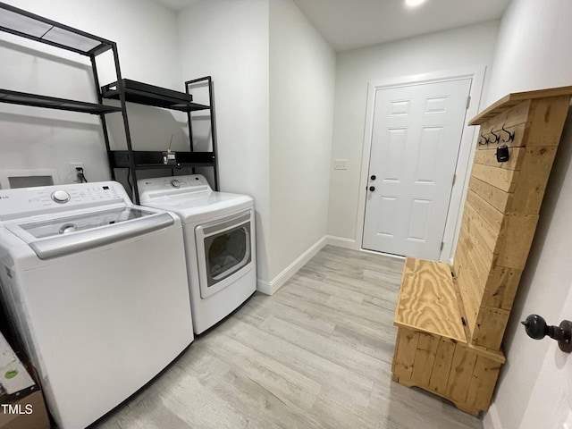 laundry area with baseboards, light wood-type flooring, washer and dryer, and laundry area