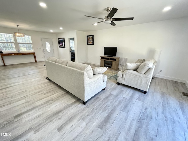 living room with ceiling fan with notable chandelier, recessed lighting, wood finished floors, and a healthy amount of sunlight